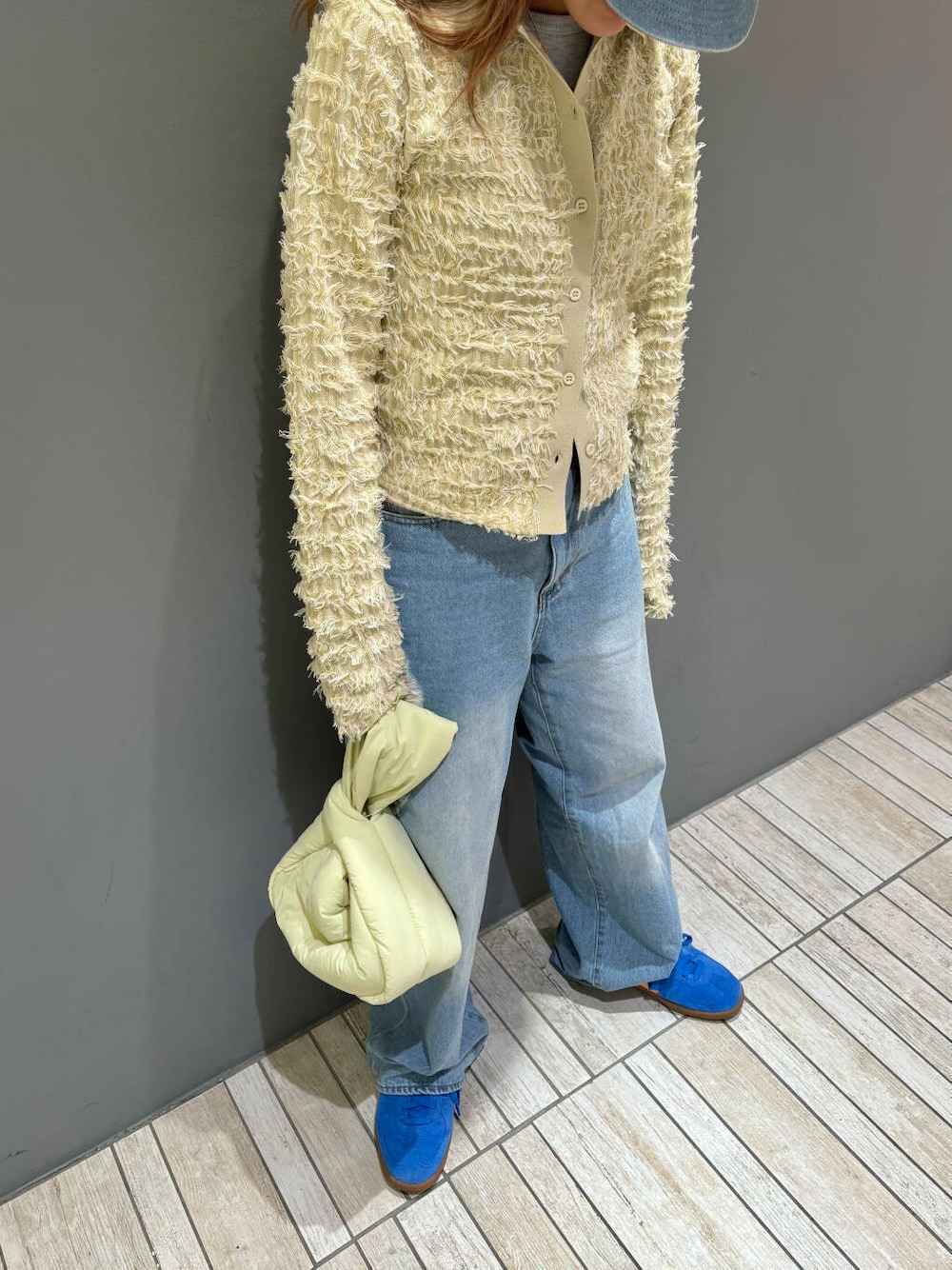 ベージュ系のニット/セーター、ブルー系のデニムパンツ、グリーン系のハンドバッグを着用したレディースの秋コーディネートの2枚目の写真