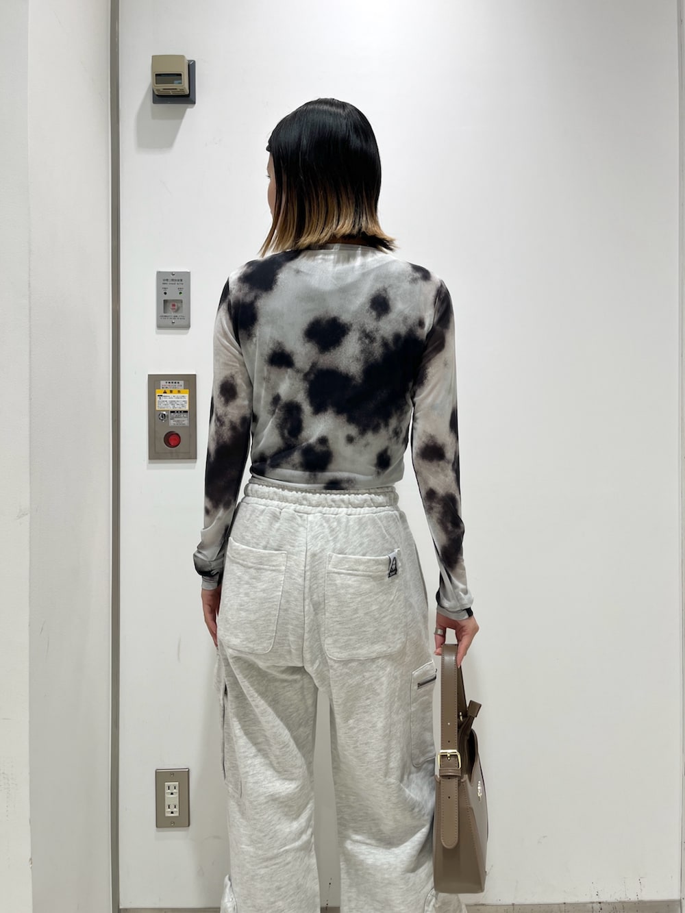 ブラック系のTシャツ/カットソー、グレー系のスウェットパンツ、ベージュ系のハンドバッグを着用したレディースの夏コーディネートの4枚目の写真