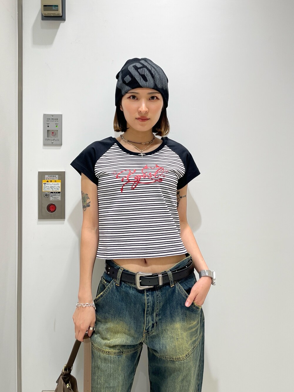 ブルー系のデニムパンツ、ホワイト系のTシャツ/カットソー、ベージュ系のハンドバッグを着用したレディースの夏コーディネートの3枚目の写真