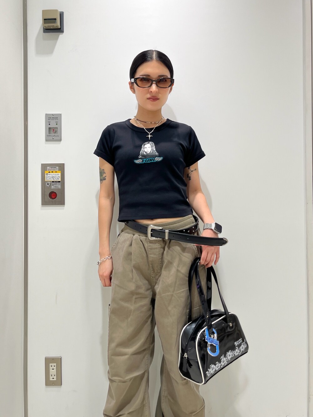 ブラック系のTシャツ/カットソー、ベージュ系のその他パンツ、ブラック系のハンドバッグを着用したレディースの夏コーディネートの3枚目の写真