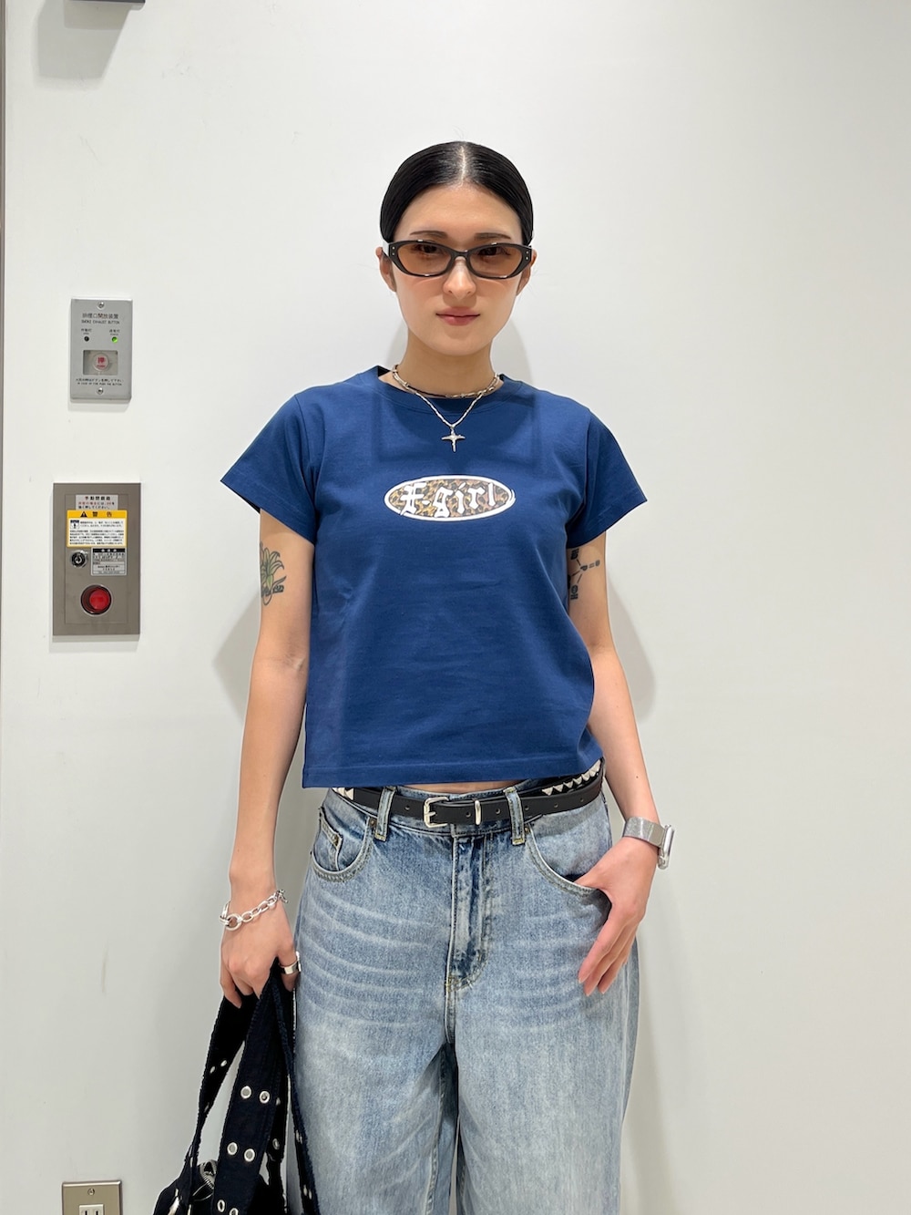 ブルー系のデニムパンツ、ブラック系のハンドバッグ、ブルー系のTシャツ/カットソーを着用したレディースの夏コーディネートの3枚目の写真