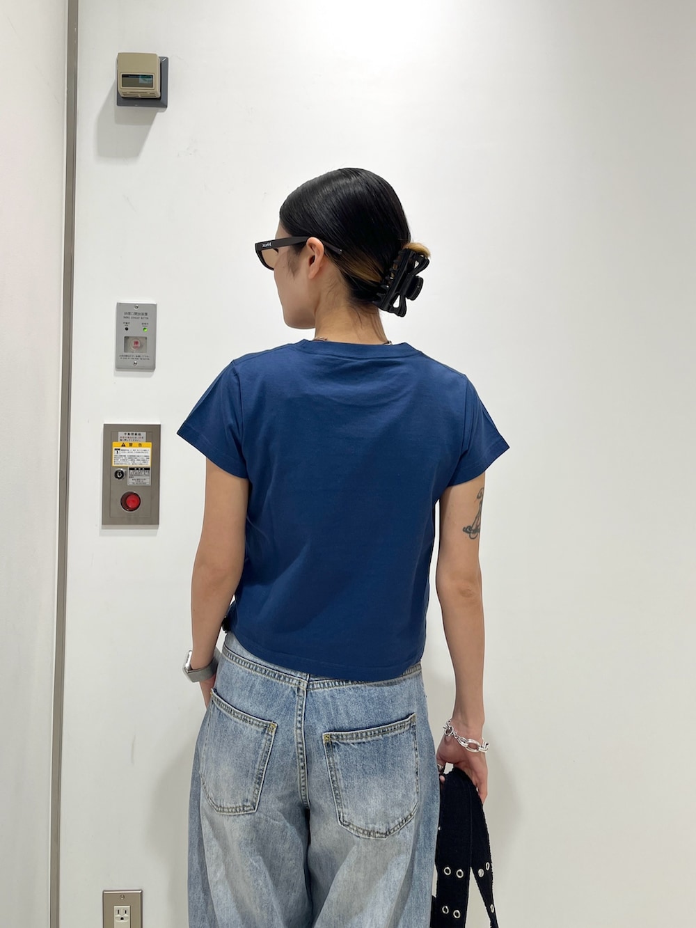 ブルー系のデニムパンツ、ブラック系のハンドバッグ、ブルー系のTシャツ/カットソーを着用したレディースの夏コーディネートの4枚目の写真
