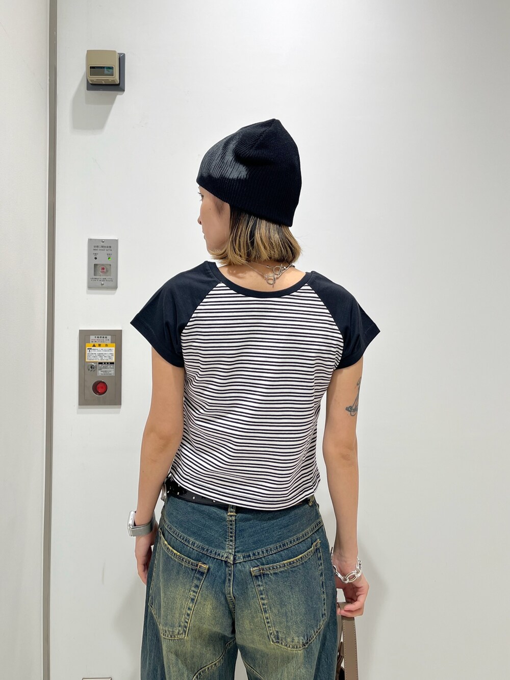 ブルー系のデニムパンツ、ホワイト系のTシャツ/カットソー、ベージュ系のハンドバッグを着用したレディースの夏コーディネートの4枚目の写真