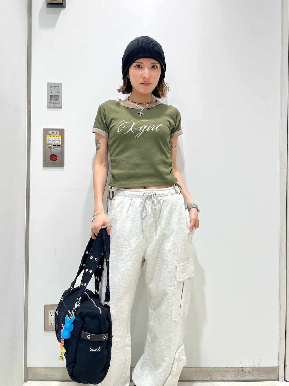 グレー系のスウェットパンツ、グリーン系のTシャツ/カットソー、ブラック系のハンドバッグを着用したレディースの春コーディネートの2枚目の写真