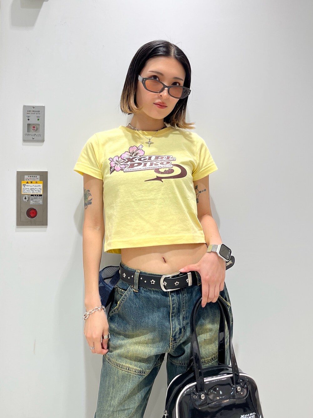 ブルー系のデニムパンツ、ブラック系のハンドバッグ、イエロー系のTシャツ/カットソーを着用したレディースの春コーディネートの4枚目の写真