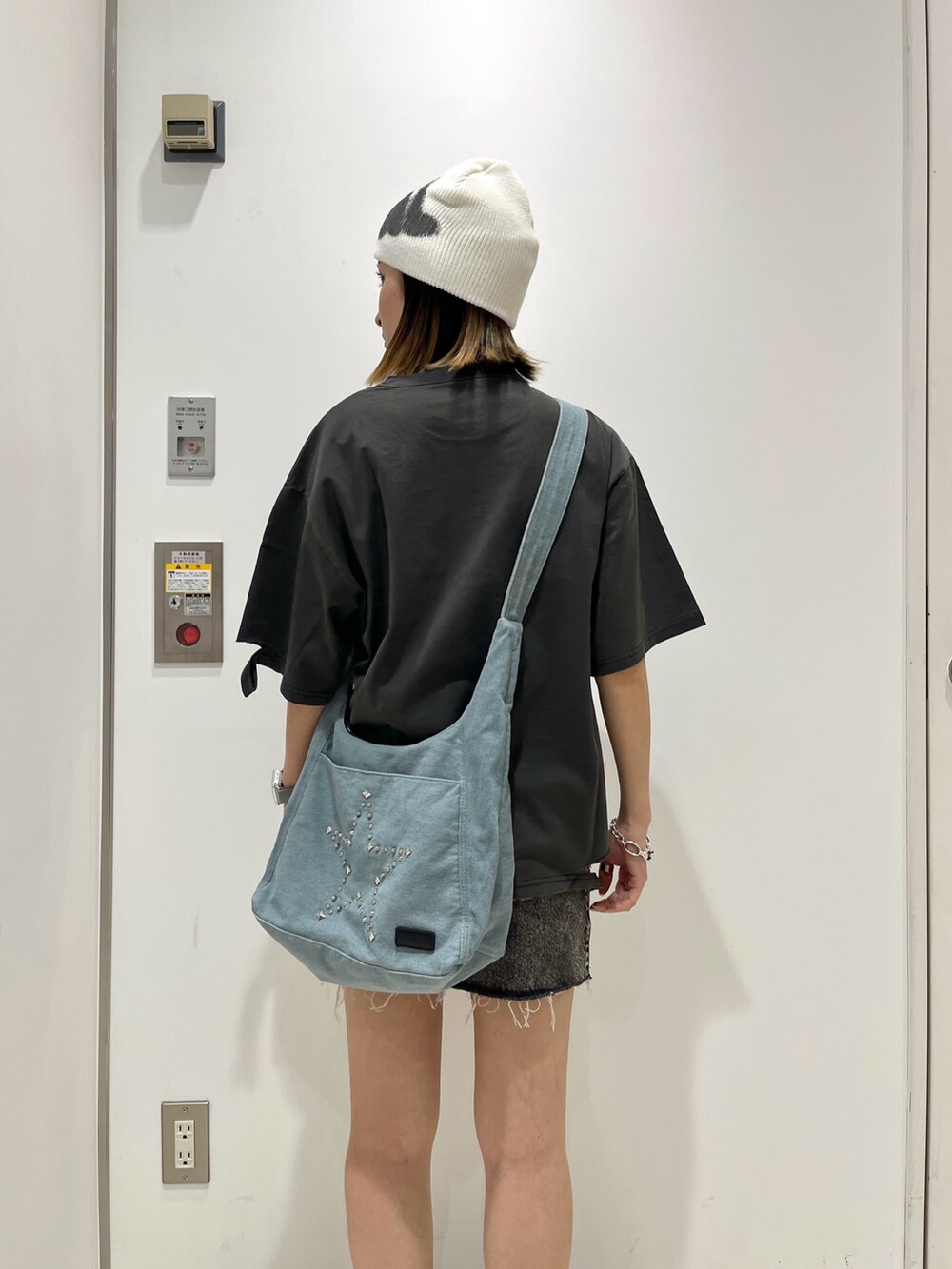ブラック系のTシャツ/カットソー、ブラック系のデニムスカート、ブルー系のショルダーバッグを着用したレディースの夏コーディネートの5枚目の写真