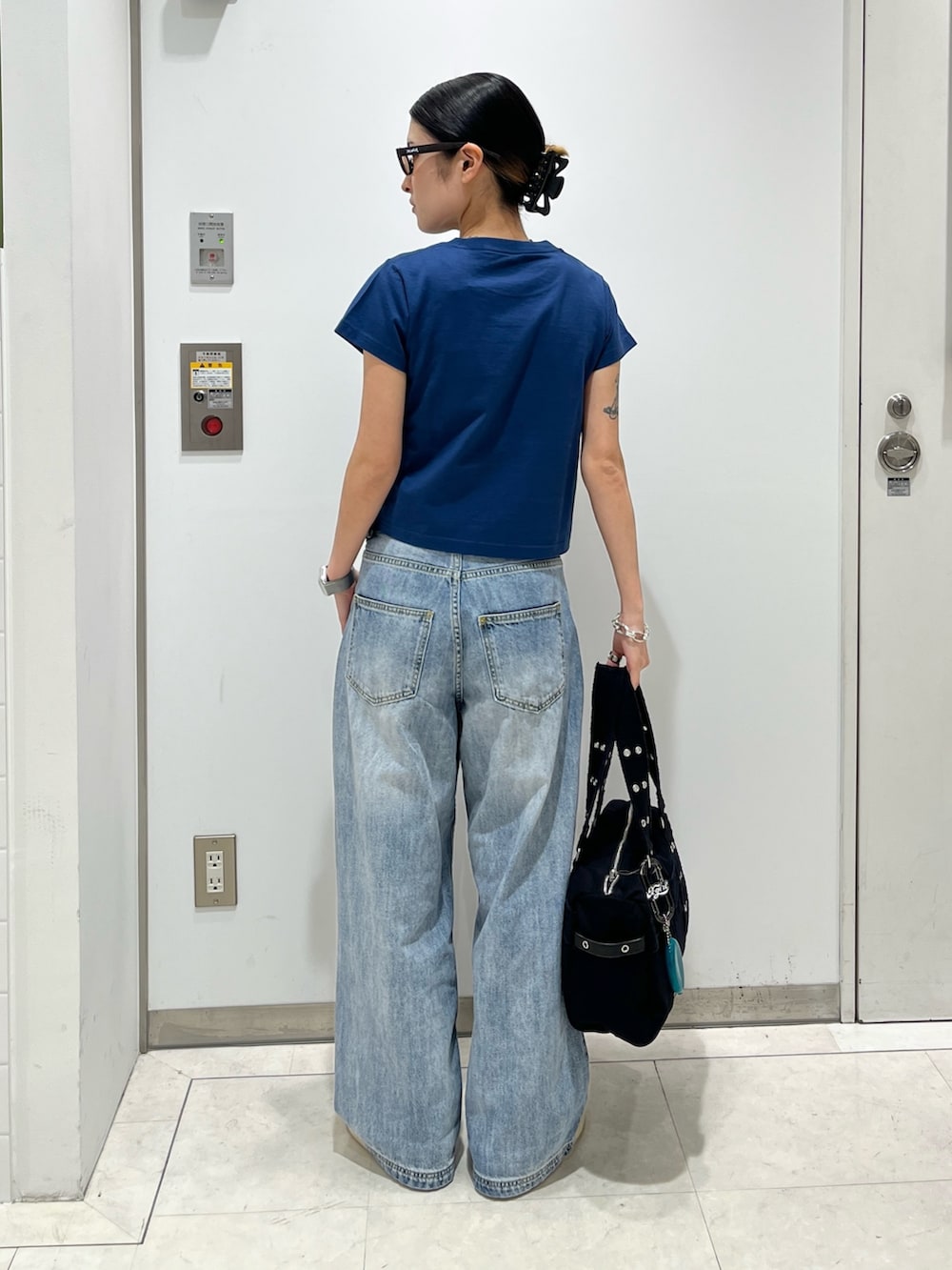 ブルー系のデニムパンツ、ブラック系のハンドバッグ、ブルー系のTシャツ/カットソーを着用したレディースの夏コーディネートの2枚目の写真