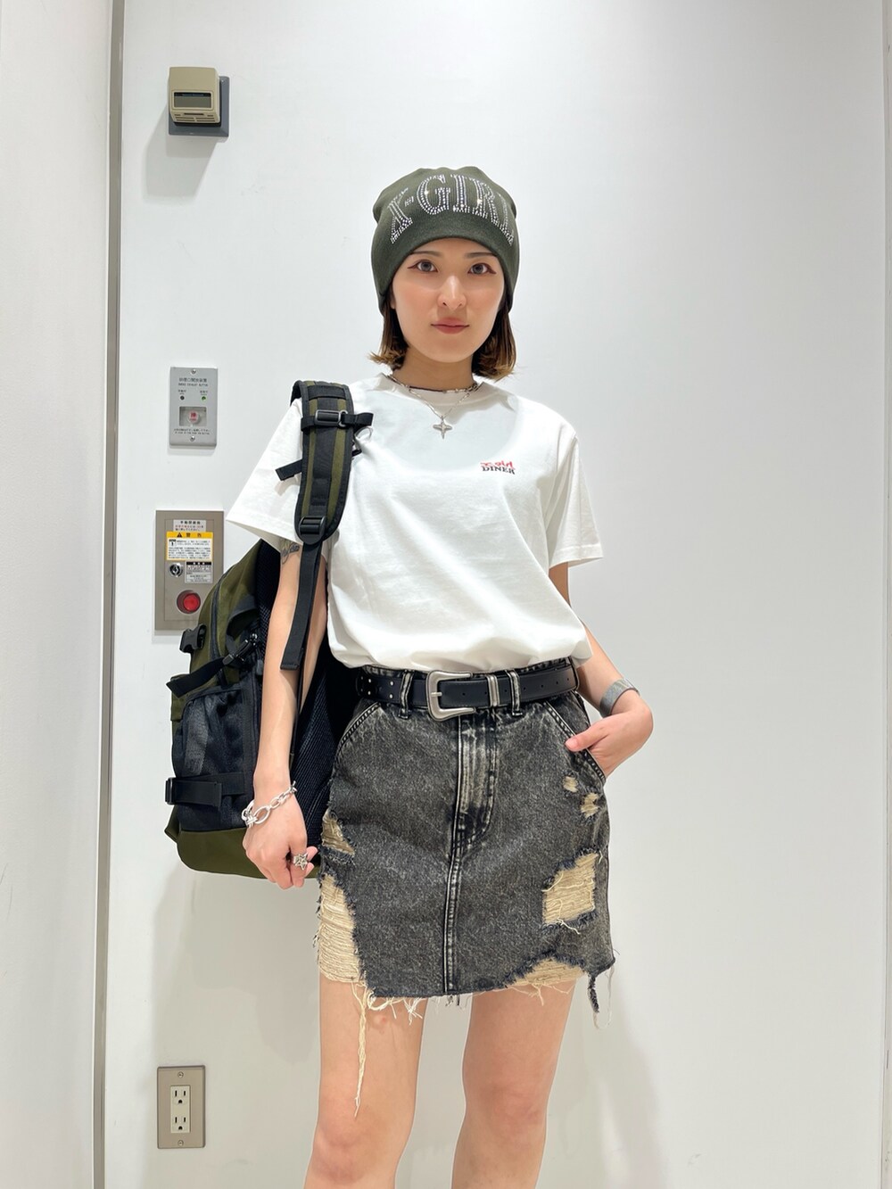 ブラック系のデニムスカート、グリーン系のバックパック/リュック、ホワイト系のTシャツ/カットソーを着用したレディースの夏コーディネートの4枚目の写真