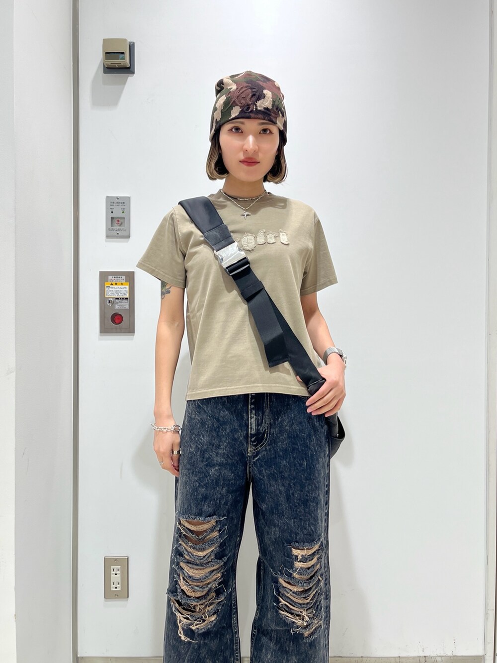 ブルー系のデニムパンツ、ベージュ系のTシャツ/カットソー、ブラック系のショルダーバッグを着用したレディースの春コーディネートの3枚目の写真