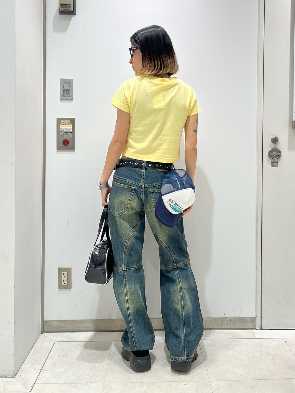 ブルー系のデニムパンツ、ブラック系のハンドバッグ、イエロー系のTシャツ/カットソーを着用したレディースの春コーディネートの3枚目の写真