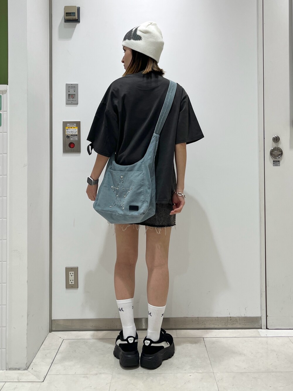 ブラック系のTシャツ/カットソー、ブラック系のデニムスカート、ブルー系のショルダーバッグを着用したレディースの夏コーディネートの2枚目の写真