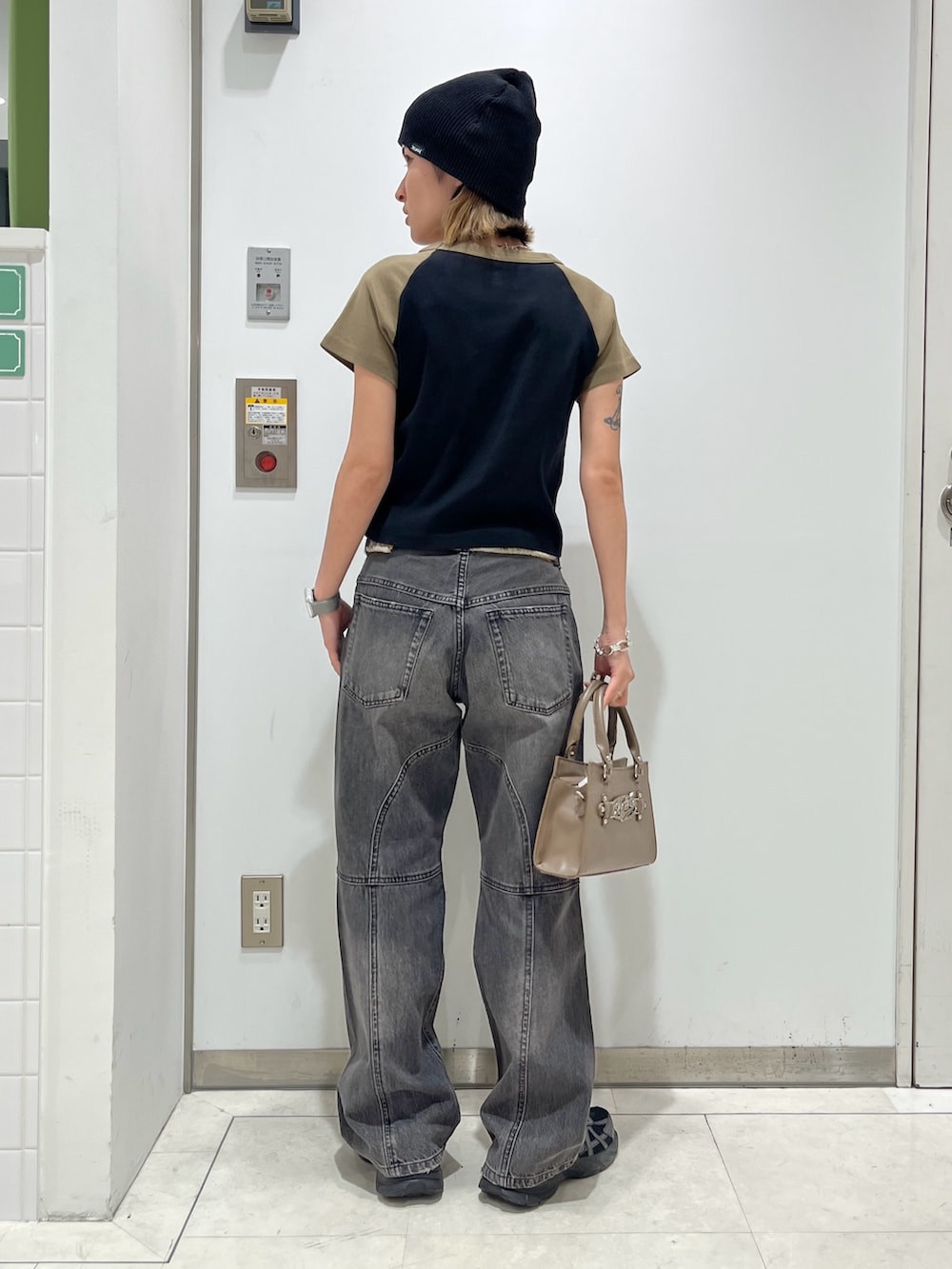 ブラック系のTシャツ/カットソー、ブラウン系のショルダーバッグ、ブラック系のデニムパンツを着用したレディースの春コーディネートの2枚目の写真