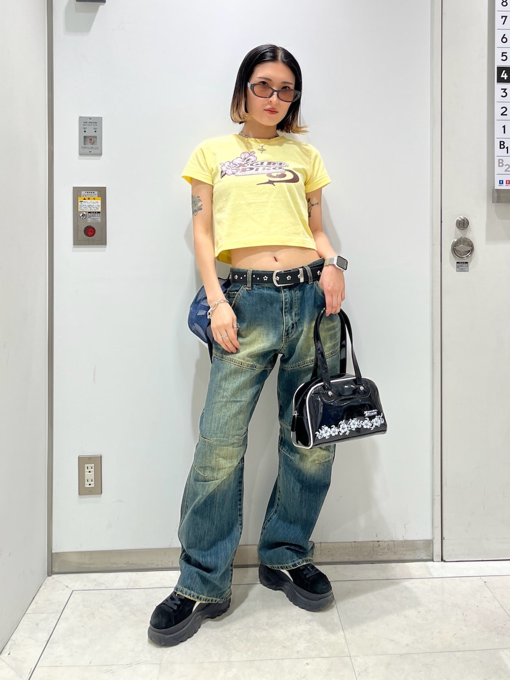 ブルー系のデニムパンツ、ブラック系のハンドバッグ、イエロー系のTシャツ/カットソーを着用したレディースの春コーディネートの2枚目の写真