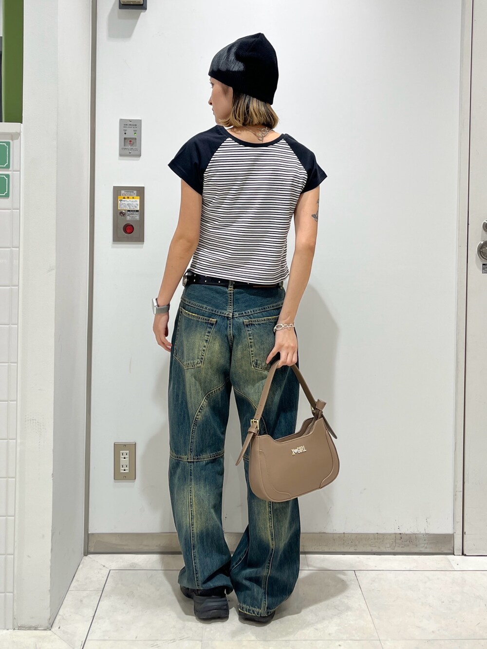 ブルー系のデニムパンツ、ホワイト系のTシャツ/カットソー、ベージュ系のハンドバッグを着用したレディースの夏コーディネートの2枚目の写真