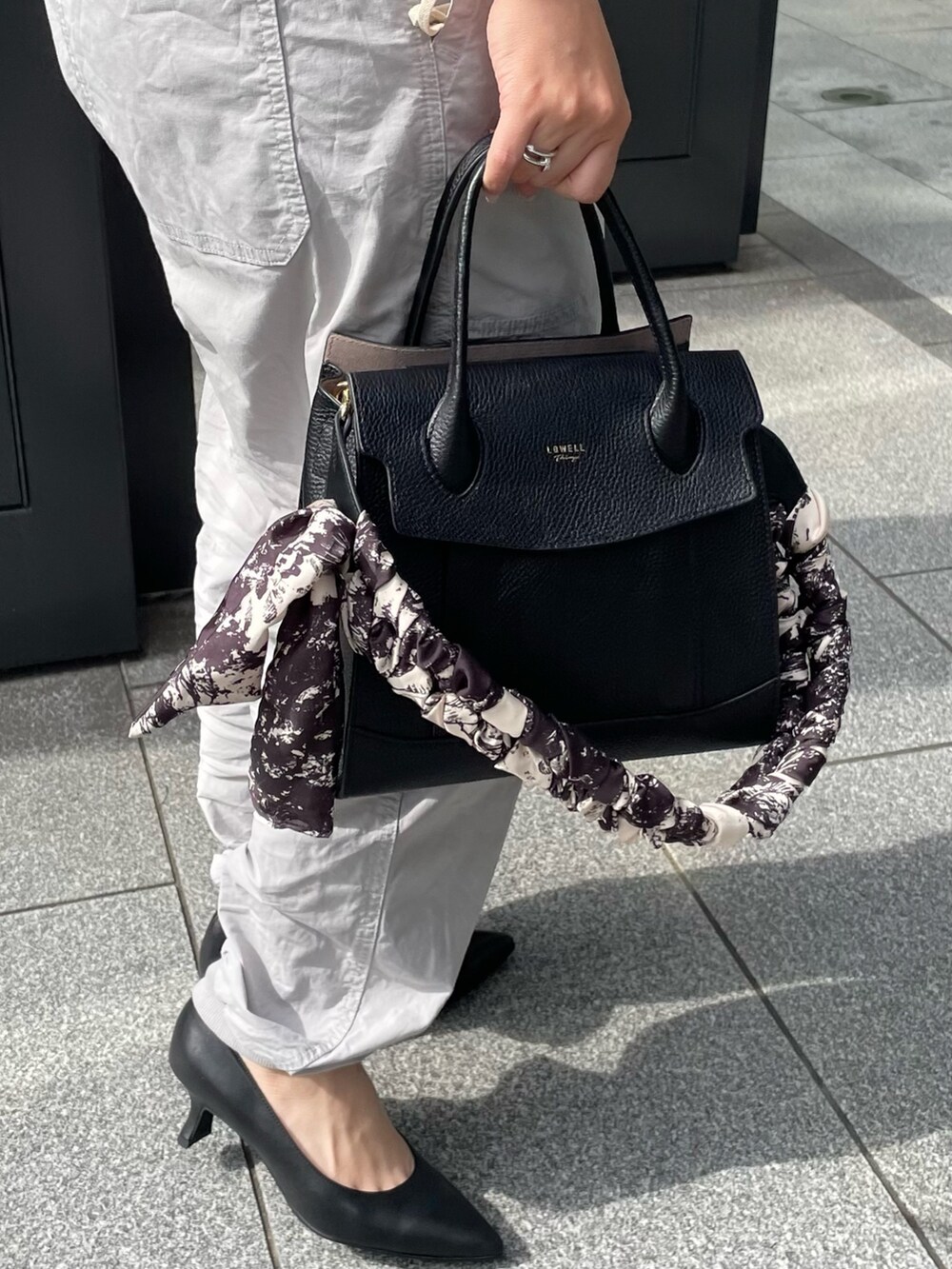 ブルー系のTシャツ/カットソー、ブラック系のショルダーバッグ、ブラック系のパンプスを着用したレディースの夏コーディネートの3枚目の写真