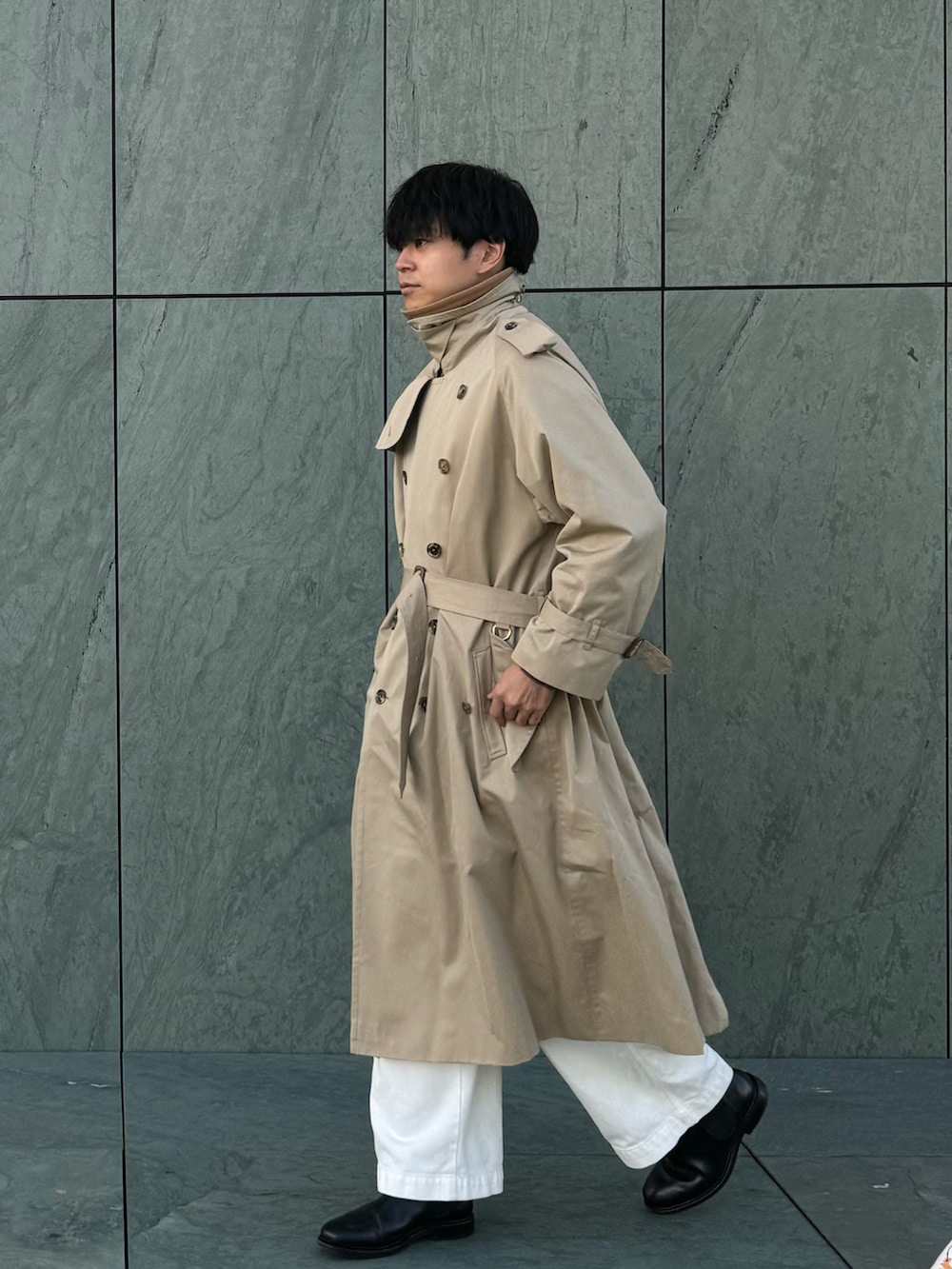 ベージュ系のトレンチコート、ブラック系のブーツ、ブラウン系のカーディガン/ボレロを着用したメンズの冬コーディネートの2枚目の写真