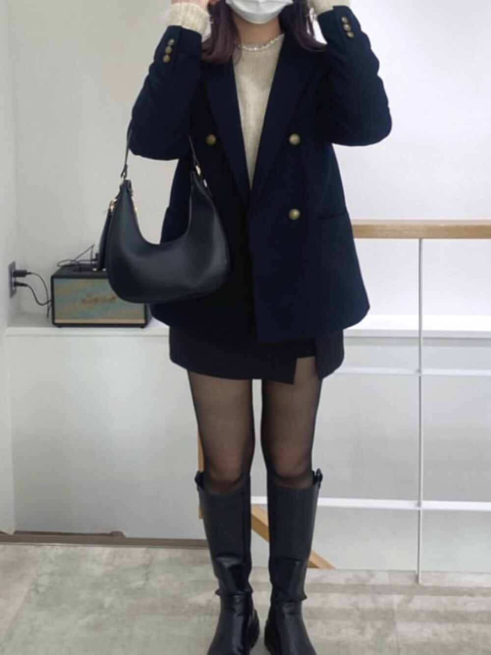 ベージュ系のニット/セーター、ブルー系のジャケット/アウター、ブラック系のハンドバッグを着用したレディースの春コーディネートの2枚目の写真