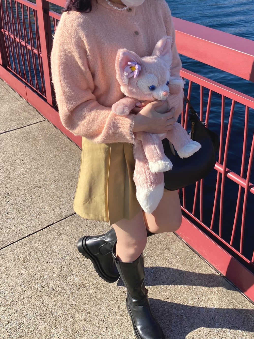 ブラック系のブーツ、ブラック系のハンドバッグ、ベージュ系のスカートを着用したレディースの春コーディネートの3枚目の写真