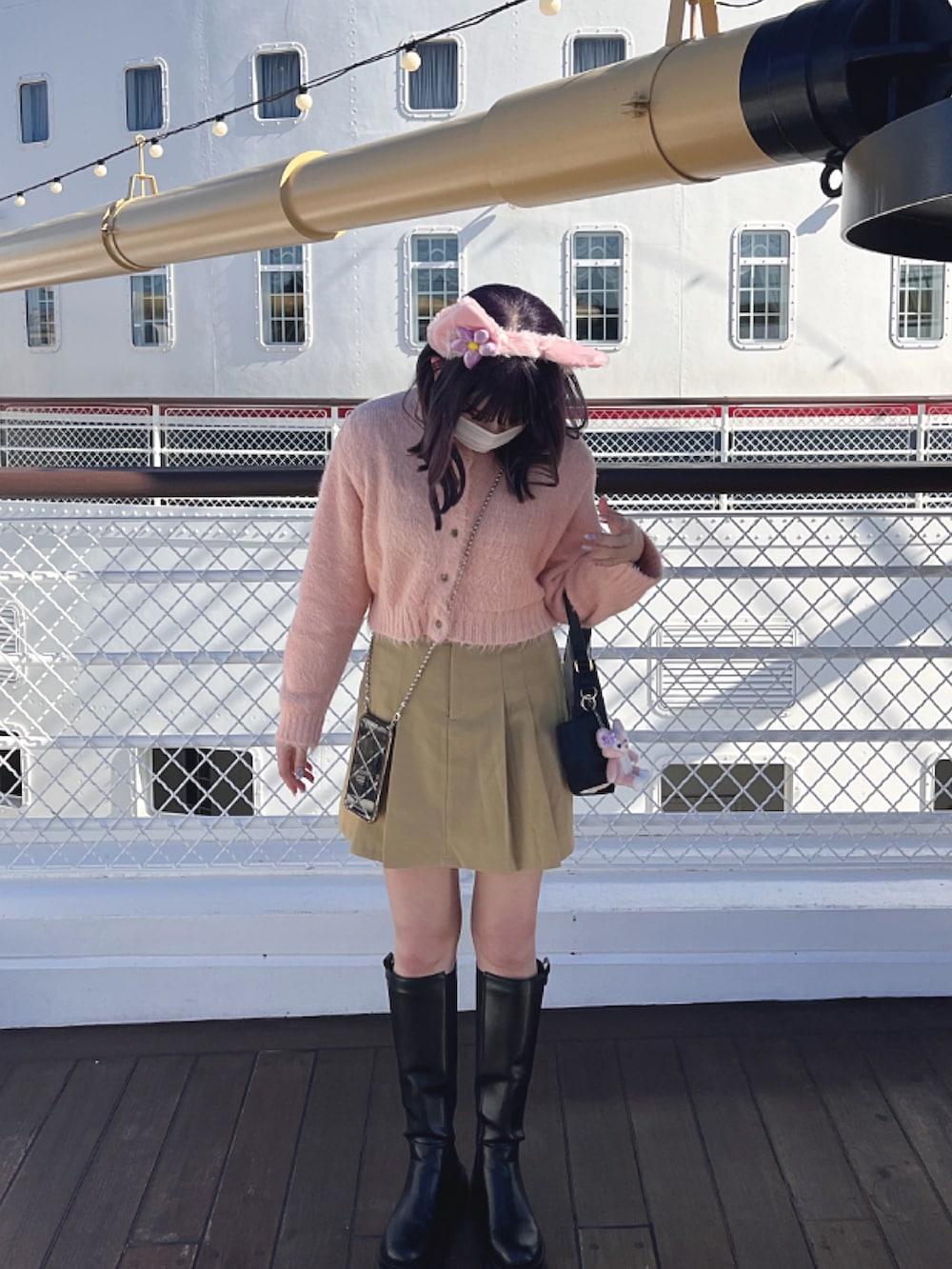 ブラック系のブーツ、ブラック系のハンドバッグ、ベージュ系のスカートを着用したレディースの春コーディネートの2枚目の写真