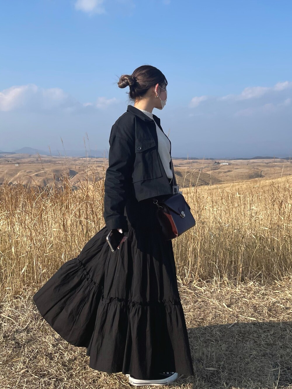 ブラック系のジャケット/アウター、ホワイト系のニット/セーター、ブラック系のスカートを着用したレディースの春コーディネートの2枚目の写真