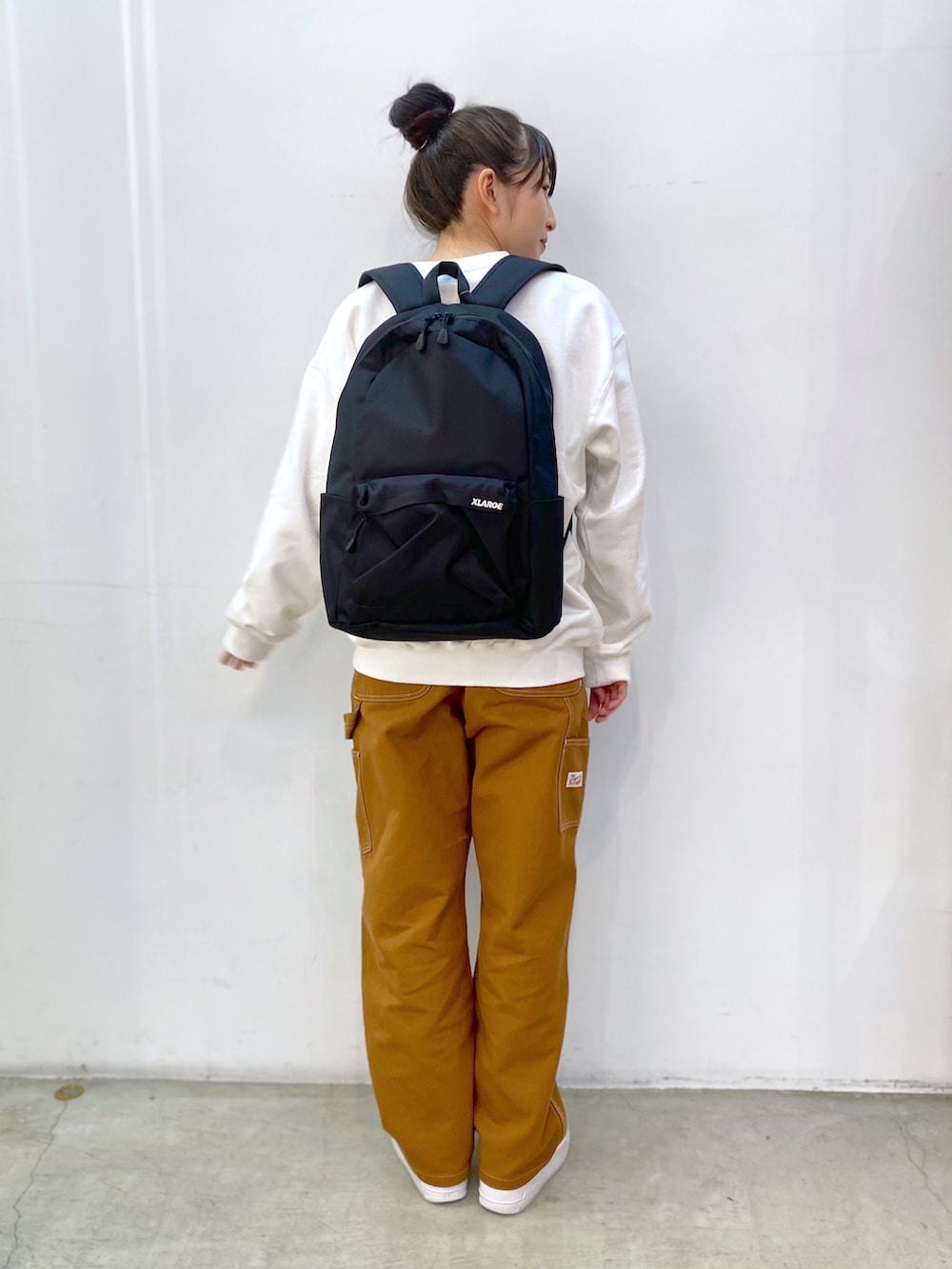 ホワイト系のスウェット、ブラウン系のその他パンツ、ブラック系のバックパック/リュックを着用したレディースの冬コーディネートの3枚目の写真