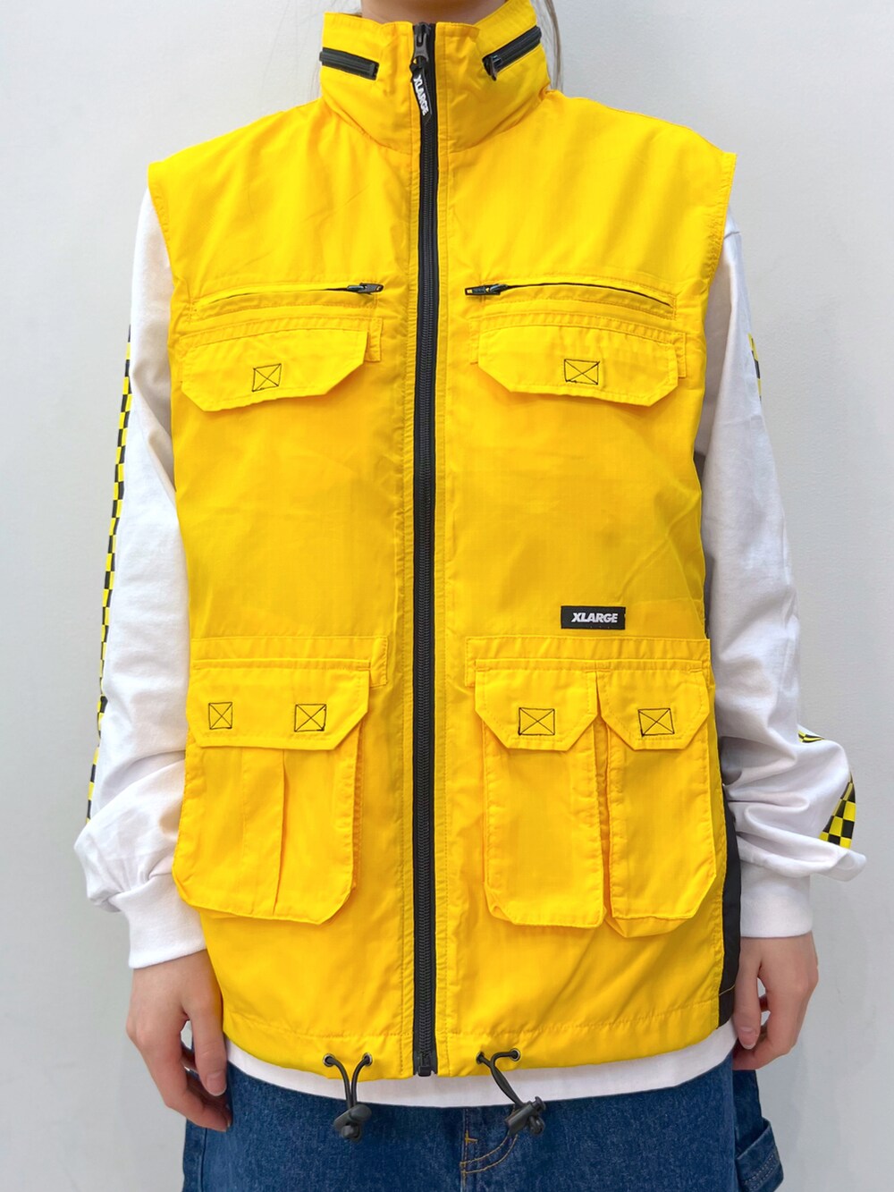 イエロー系のベスト、ホワイト系のTシャツ/カットソー、ブルー系のデニムパンツを着用したレディースの春コーディネートの4枚目の写真