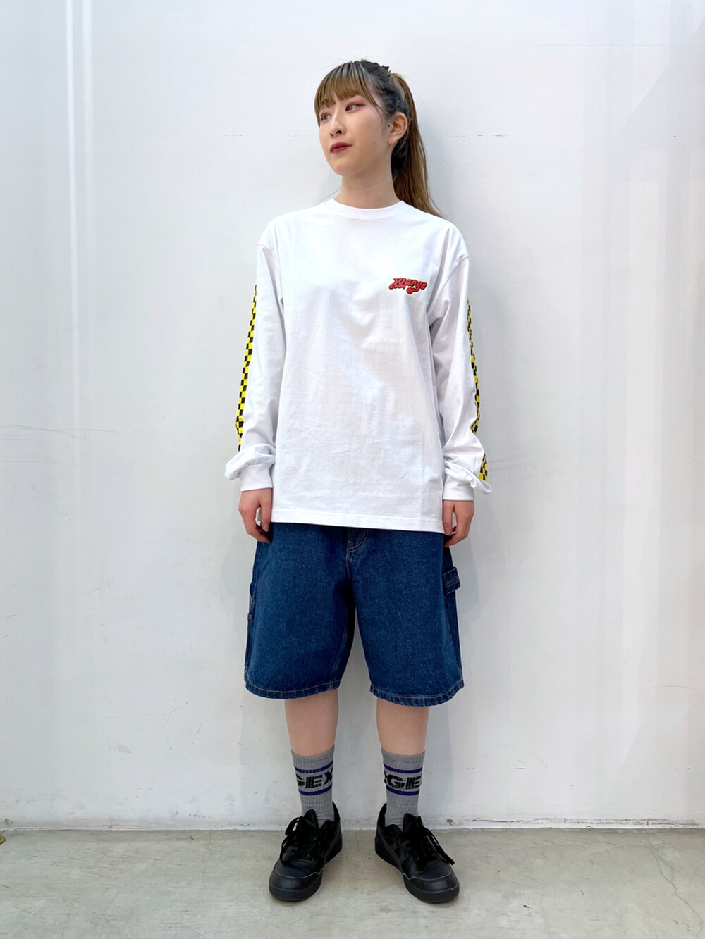 イエロー系のベスト、ホワイト系のTシャツ/カットソー、ブルー系のデニムパンツを着用したレディースの春コーディネートの2枚目の写真