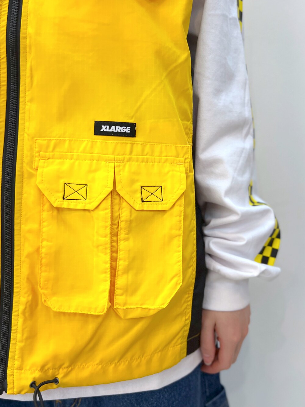 イエロー系のベスト、ホワイト系のTシャツ/カットソー、ブルー系のデニムパンツを着用したレディースの春コーディネートの5枚目の写真