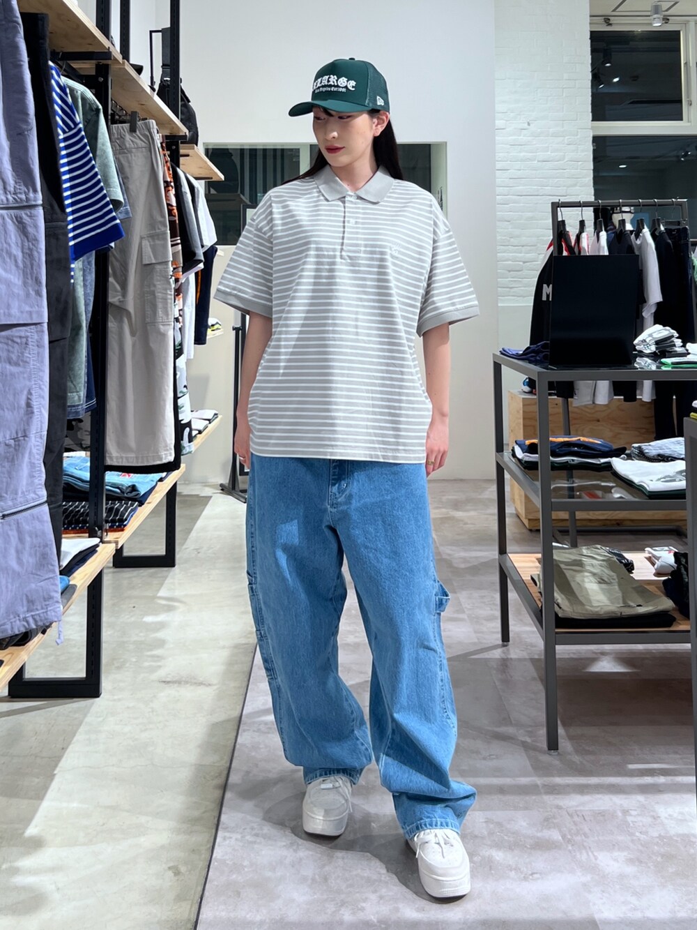 グレー系のポロシャツ、ブルー系のデニムパンツ、グリーン系のキャップを着用したレディースの春コーディネートの2枚目の写真