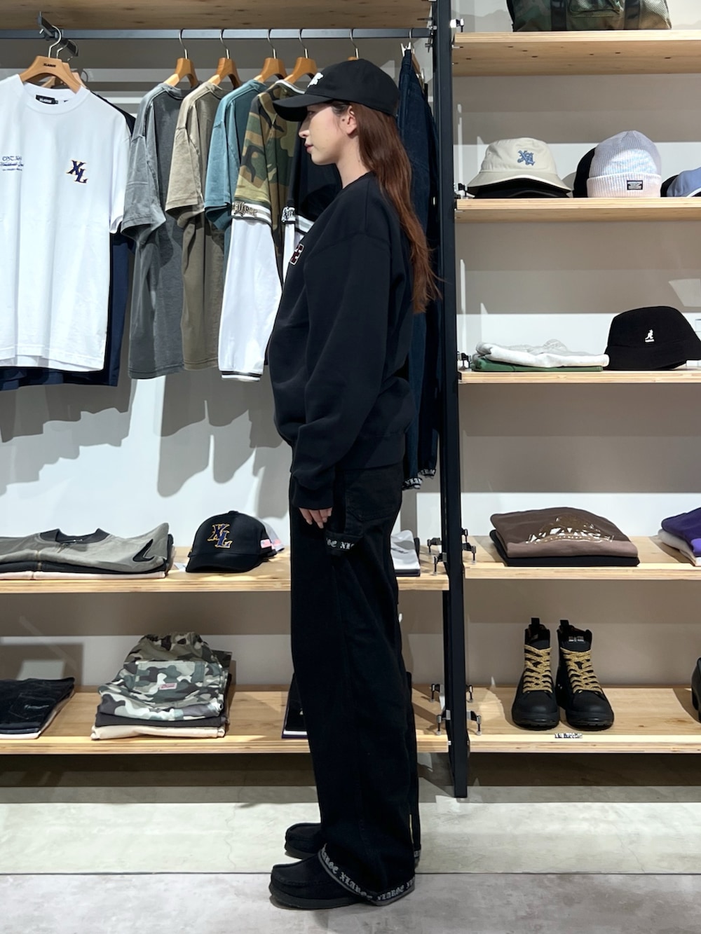 ブラック系のスウェット、ブラック系のデニムパンツ、ブラック系のキャップを着用したレディースの秋コーディネートの2枚目の写真