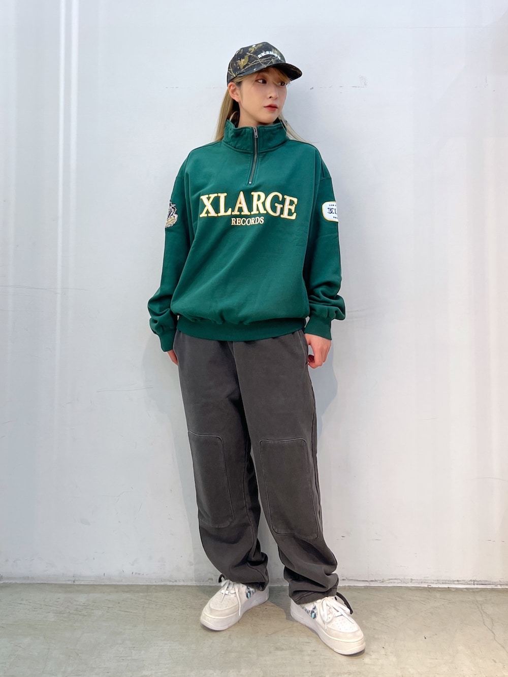 グリーン系のスウェット、ブラック系のスウェットパンツ、グリーン系のキャップを着用したレディースの秋コーディネートの2枚目の写真