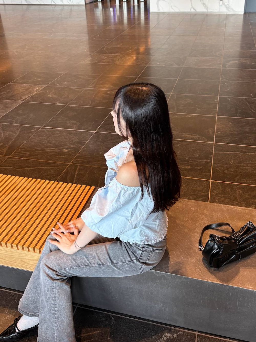 ブルー系のシャツ/ブラウス、ブラック系のショルダーバッグ、グレー系のデニムパンツを着用したレディースの夏コーディネートの3枚目の写真