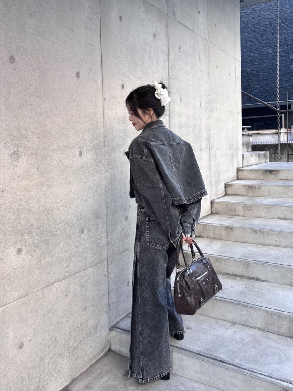 ブラウン系のボストンバッグ、ブラック系のパンプス、ブラック系のデニムジャケットを着用したレディースの冬コーディネートの4枚目の写真