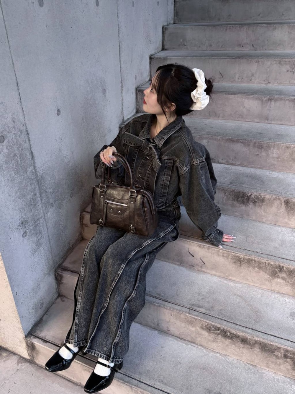 ブラウン系のボストンバッグ、ブラック系のパンプス、ブラック系のデニムジャケットを着用したレディースの冬コーディネートの6枚目の写真