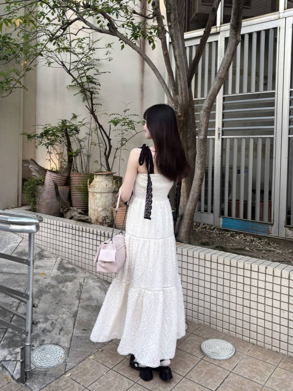ブラック系のパンプス、ホワイト系のチューブトップ、ホワイト系のワンピースを着用したレディースの春コーディネートの6枚目の写真