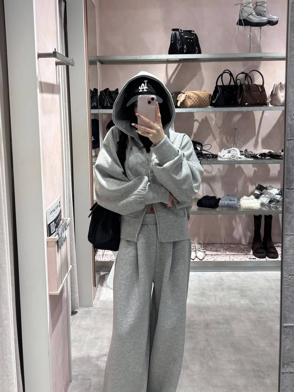 ブラック系のショルダーバッグ、グレー系のパーカー、グレー系のスウェットパンツを着用したレディースの冬コーディネートの3枚目の写真