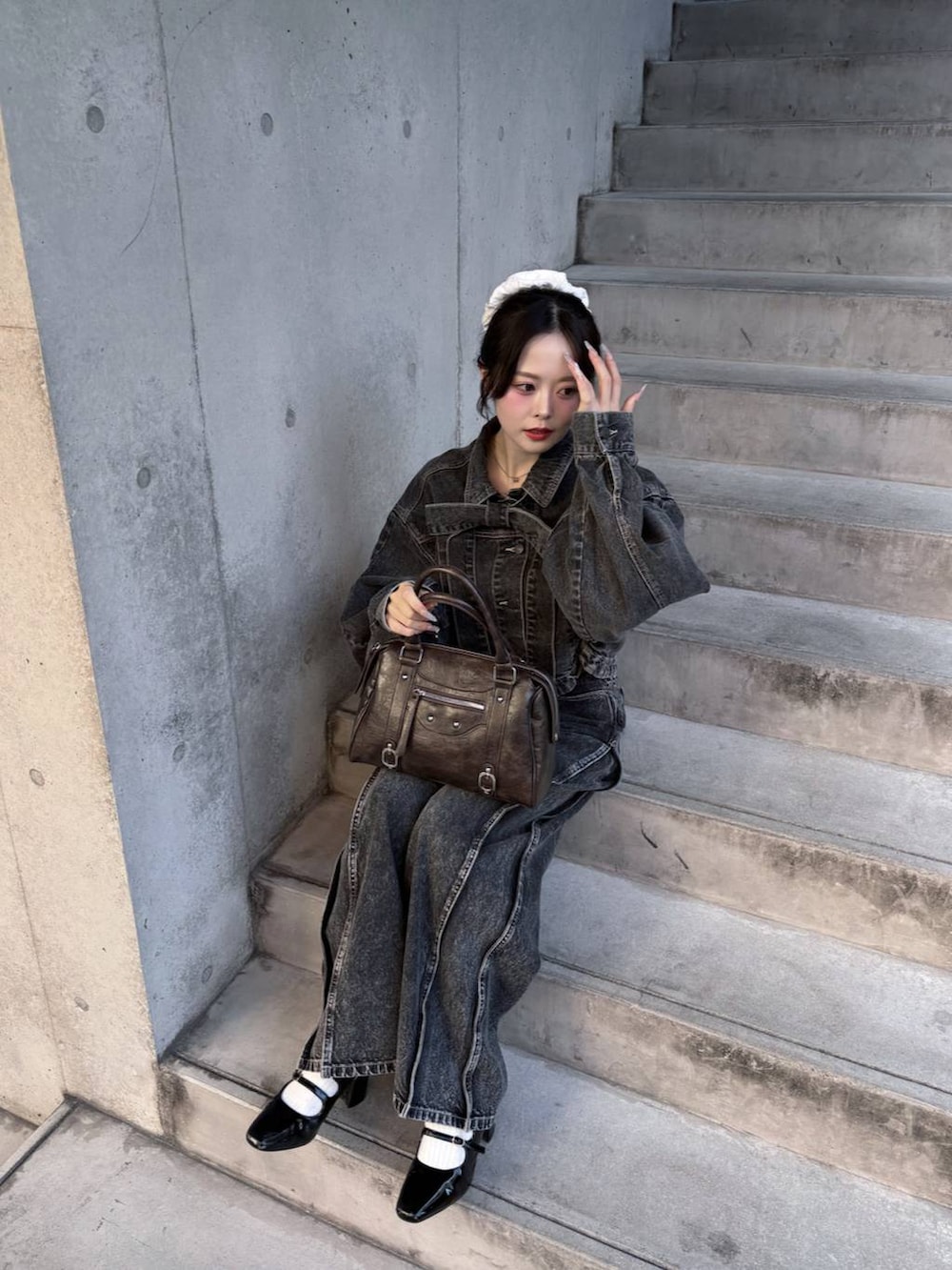 ブラウン系のボストンバッグ、ブラック系のパンプス、ブラック系のデニムジャケットを着用したレディースの冬コーディネートの5枚目の写真