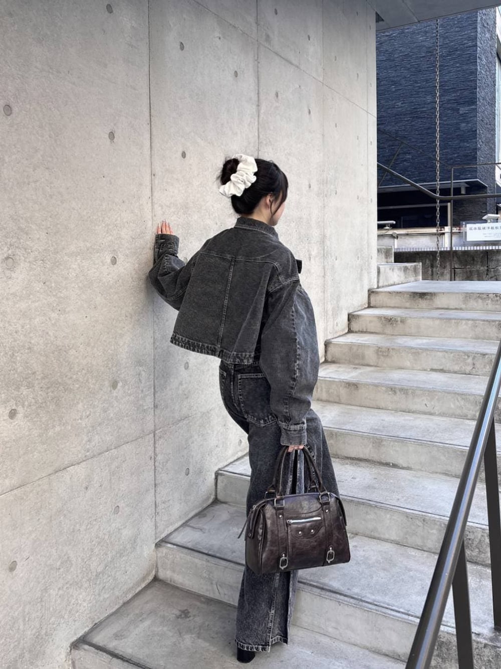 ブラウン系のボストンバッグ、ブラック系のパンプス、ブラック系のデニムジャケットを着用したレディースの冬コーディネートの7枚目の写真