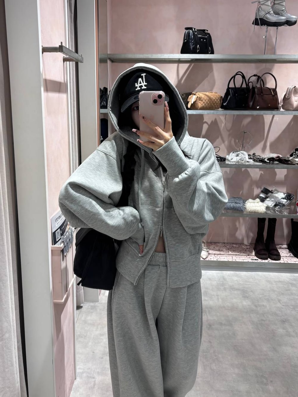 ブラック系のショルダーバッグ、グレー系のパーカー、グレー系のスウェットパンツを着用したレディースの冬コーディネートの2枚目の写真