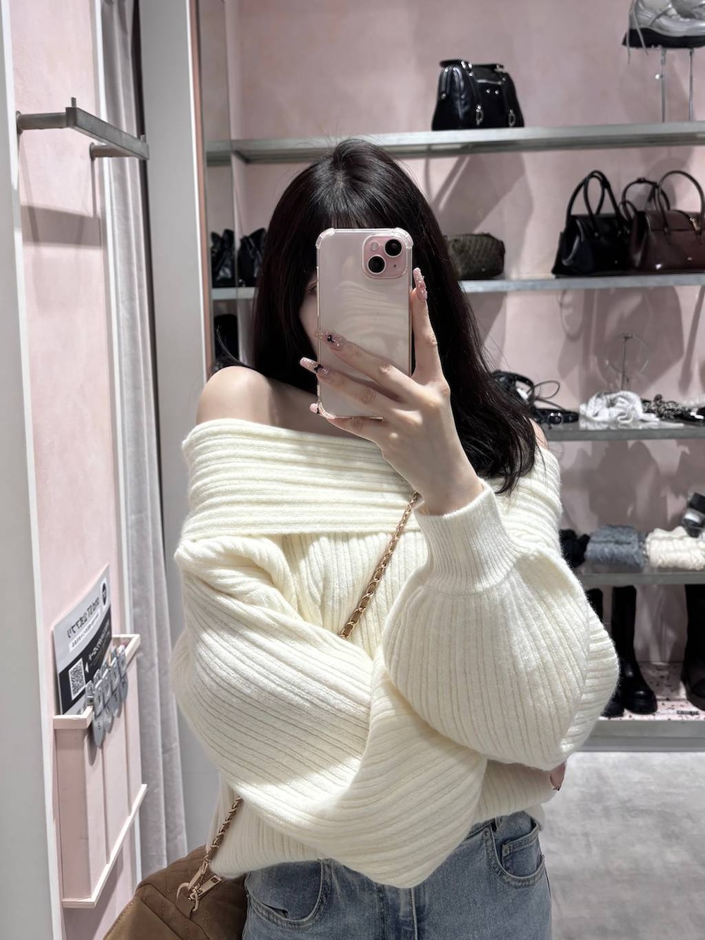 ホワイト系のニット/セーター、ブルー系のデニムパンツ、ホワイト系のパンプスを着用したレディースの冬コーディネートの5枚目の写真