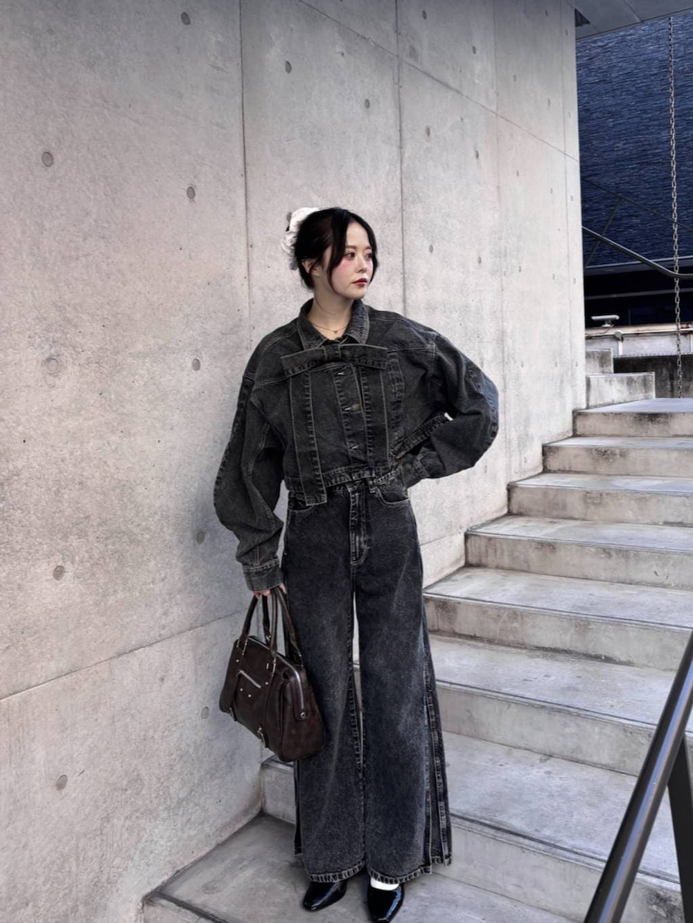 ブラウン系のボストンバッグ、ブラック系のパンプス、ブラック系のデニムジャケットを着用したレディースの冬コーディネートの3枚目の写真