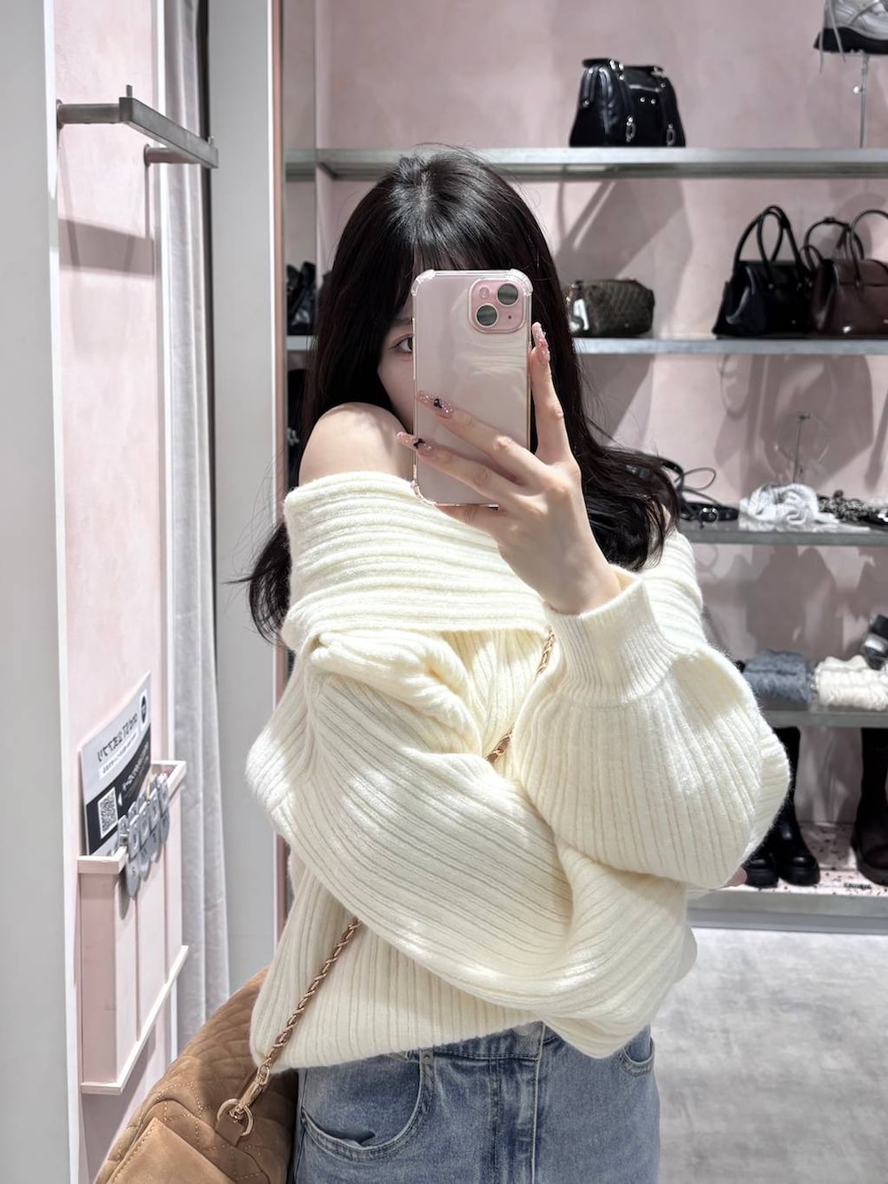 ホワイト系のニット/セーター、ブルー系のデニムパンツ、ホワイト系のパンプスを着用したレディースの冬コーディネートの7枚目の写真