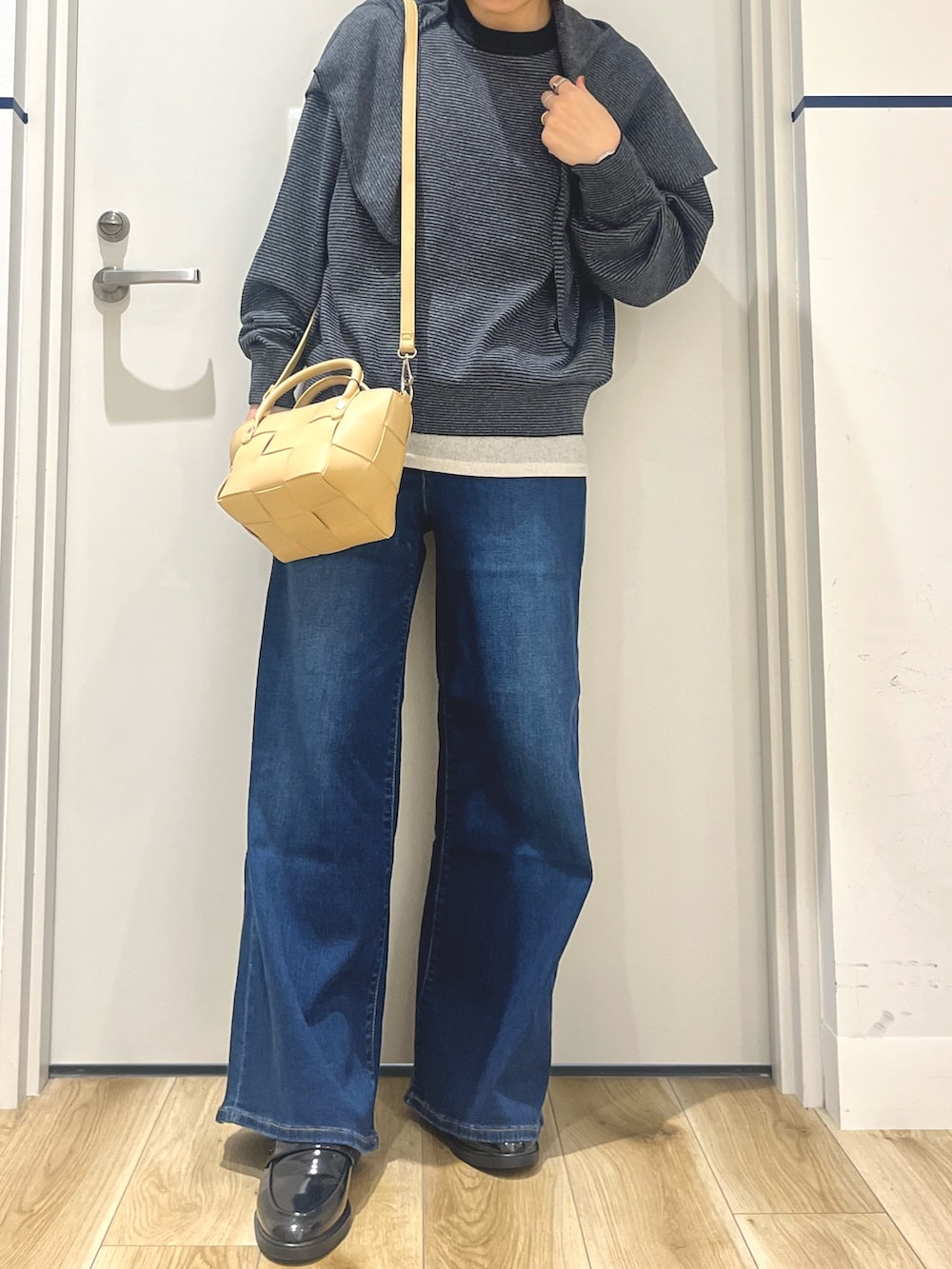 ブラック系のローファー、ブルー系のデニムパンツ、ブラック系のニット/セーターを着用したレディースの秋コーディネートの4枚目の写真