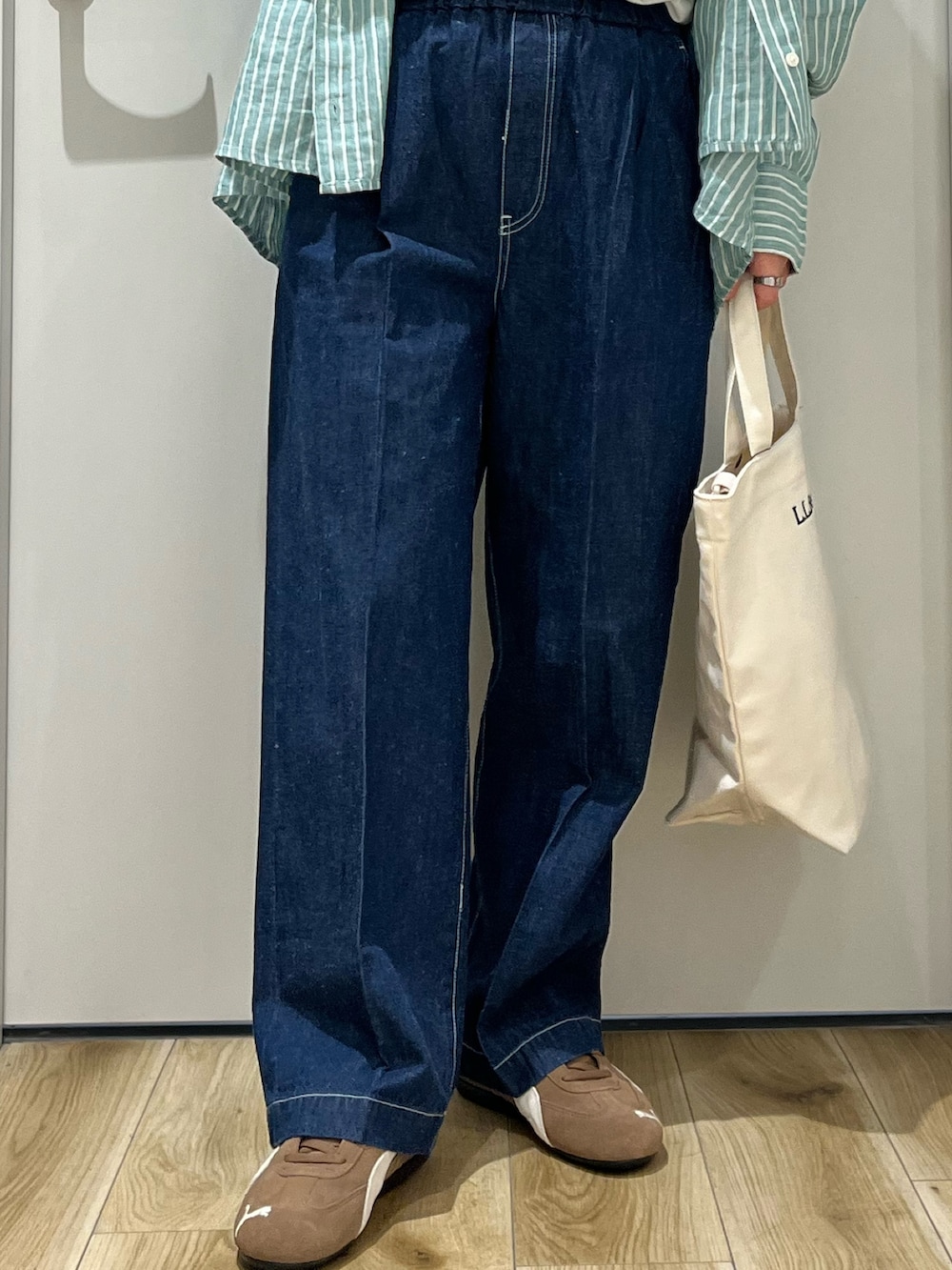 ブラウン系のスニーカー、ブルー系のデニムパンツ、ベージュ系のショルダーバッグを着用したレディースの春コーディネートの5枚目の写真