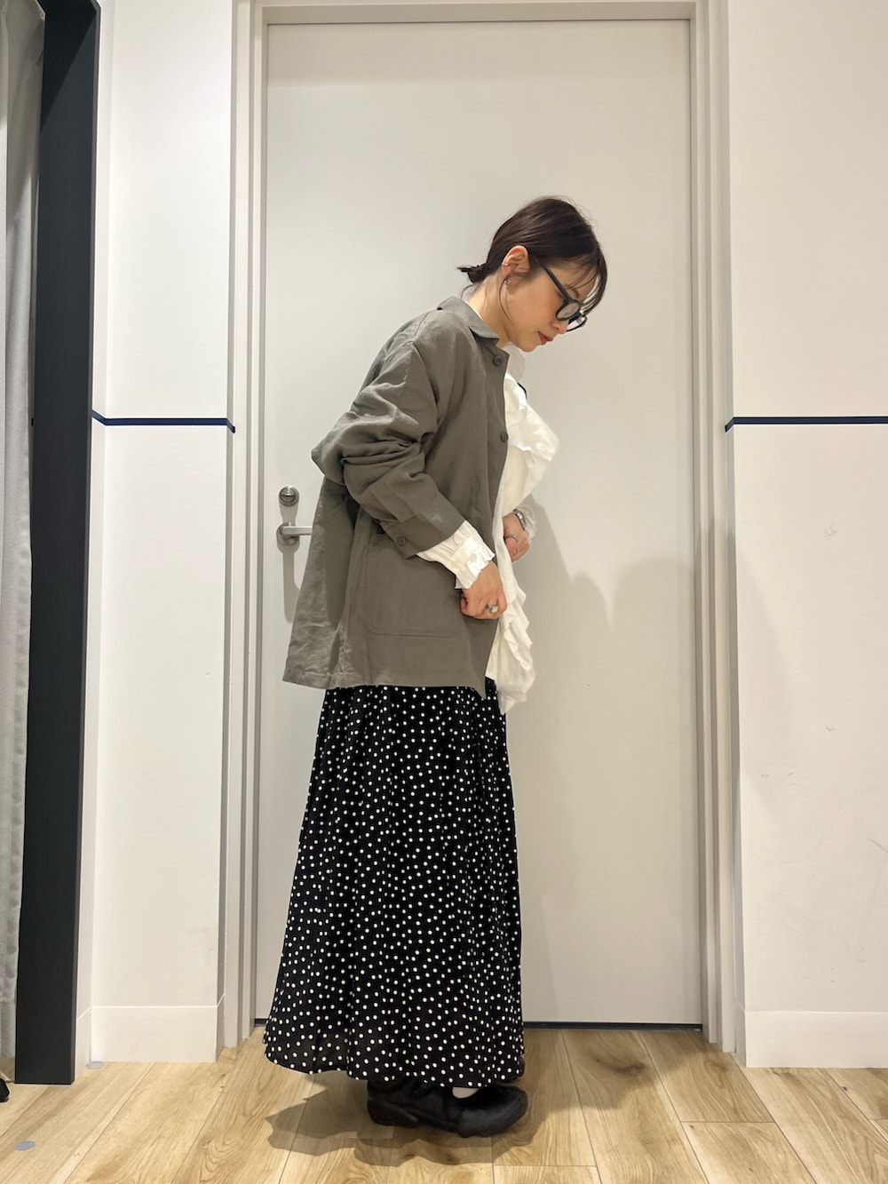 ブラック系のスニーカー、ブラック系のスカート、グレー系のカバーオールを着用したレディースの春コーディネートの2枚目の写真