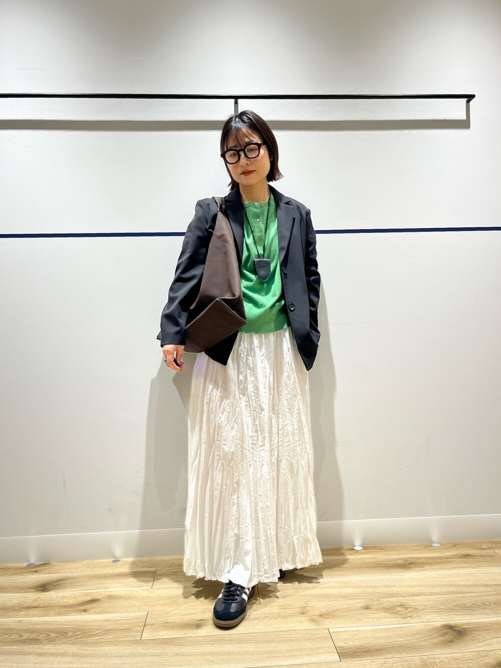 ブラウン系のトートバッグ、グリーン系のニット/セーター、ブラック系のその他アウターを着用したレディースの冬コーディネートの2枚目の写真