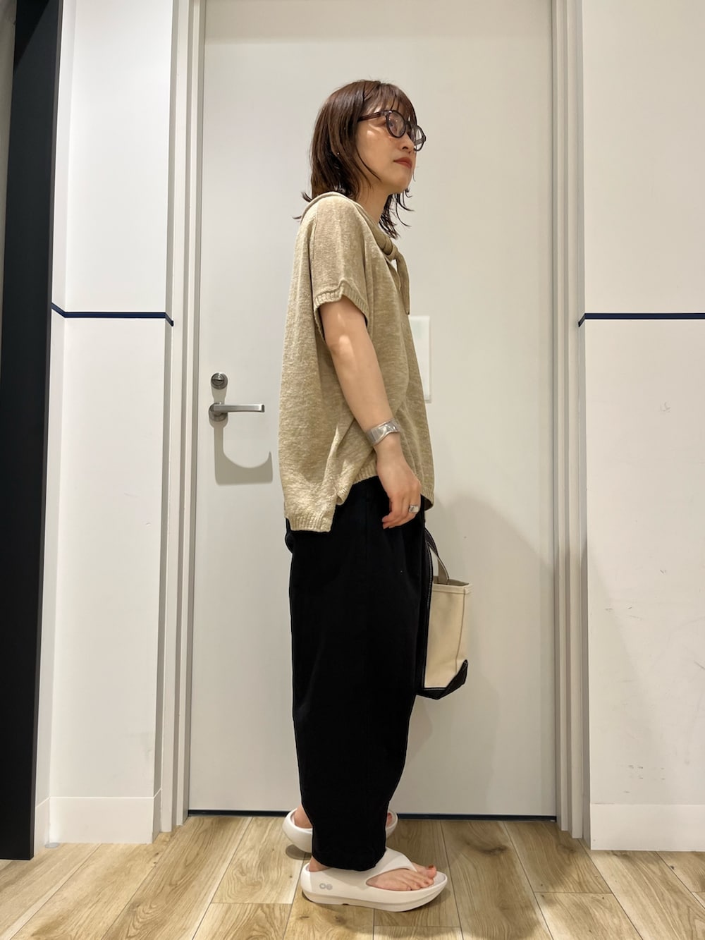 グレー系のトートバッグ、ホワイト系のサンダル、ブラック系のその他パンツを着用したレディースの春コーディネートの2枚目の写真