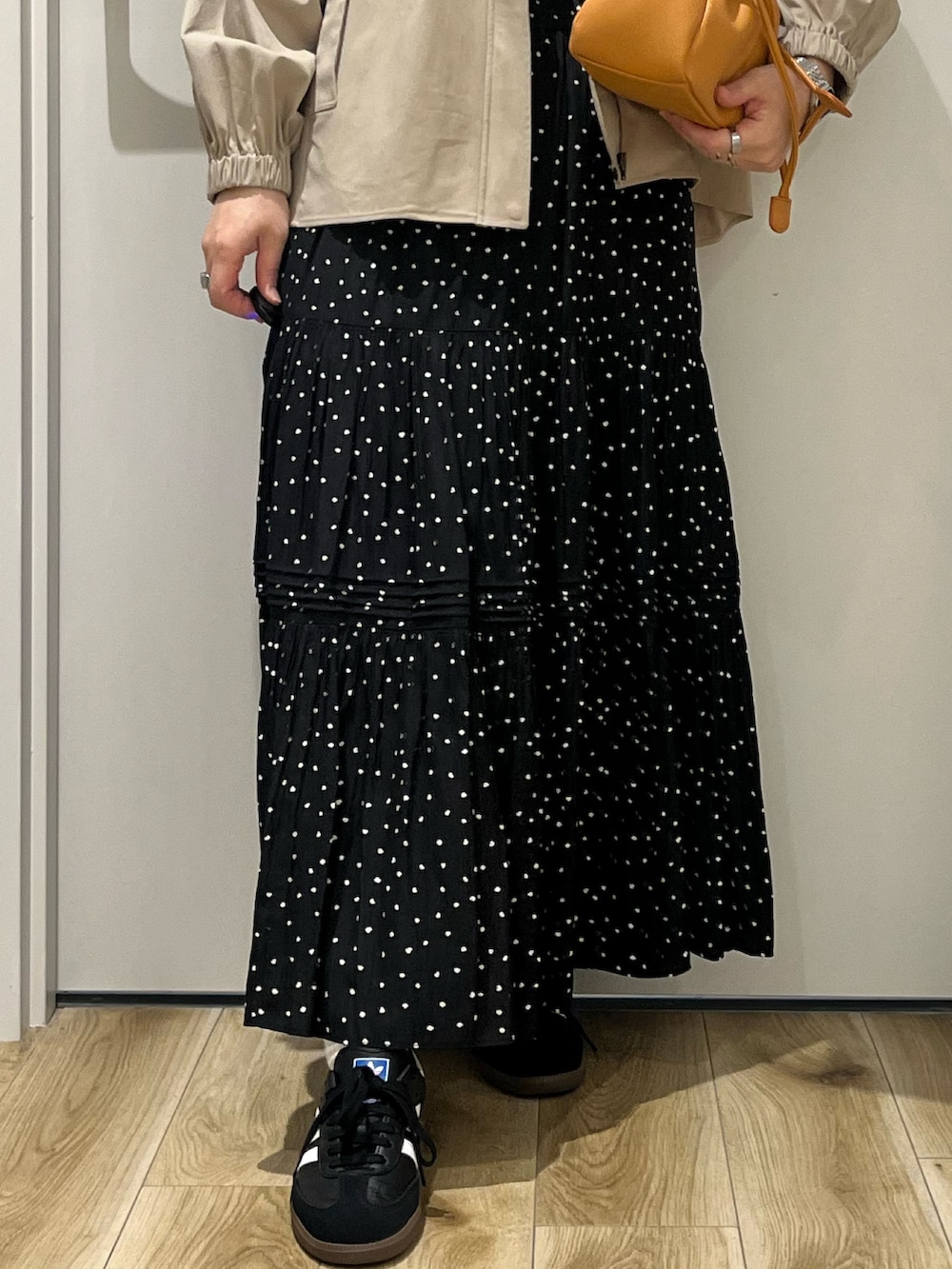 ベージュ系のその他アウター、ブラック系のスカート、オレンジ系のショルダーバッグを着用したレディースの春コーディネートの4枚目の写真