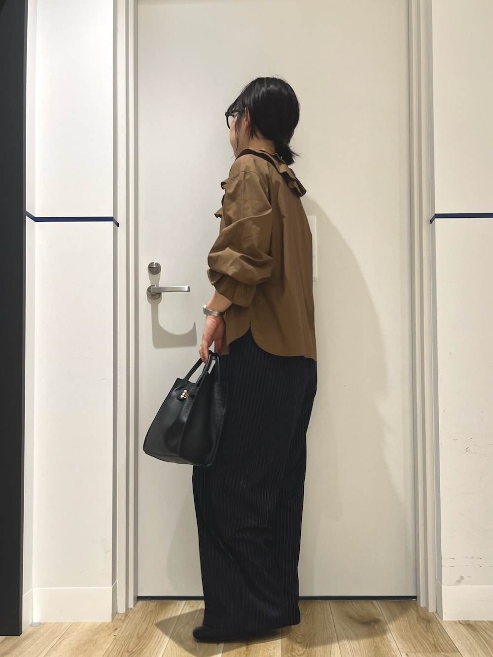 ブルー系のその他パンツ、ブラック系のハンドバッグ、ブラウン系のシャツ/ブラウスを着用したレディースの秋コーディネートの2枚目の写真