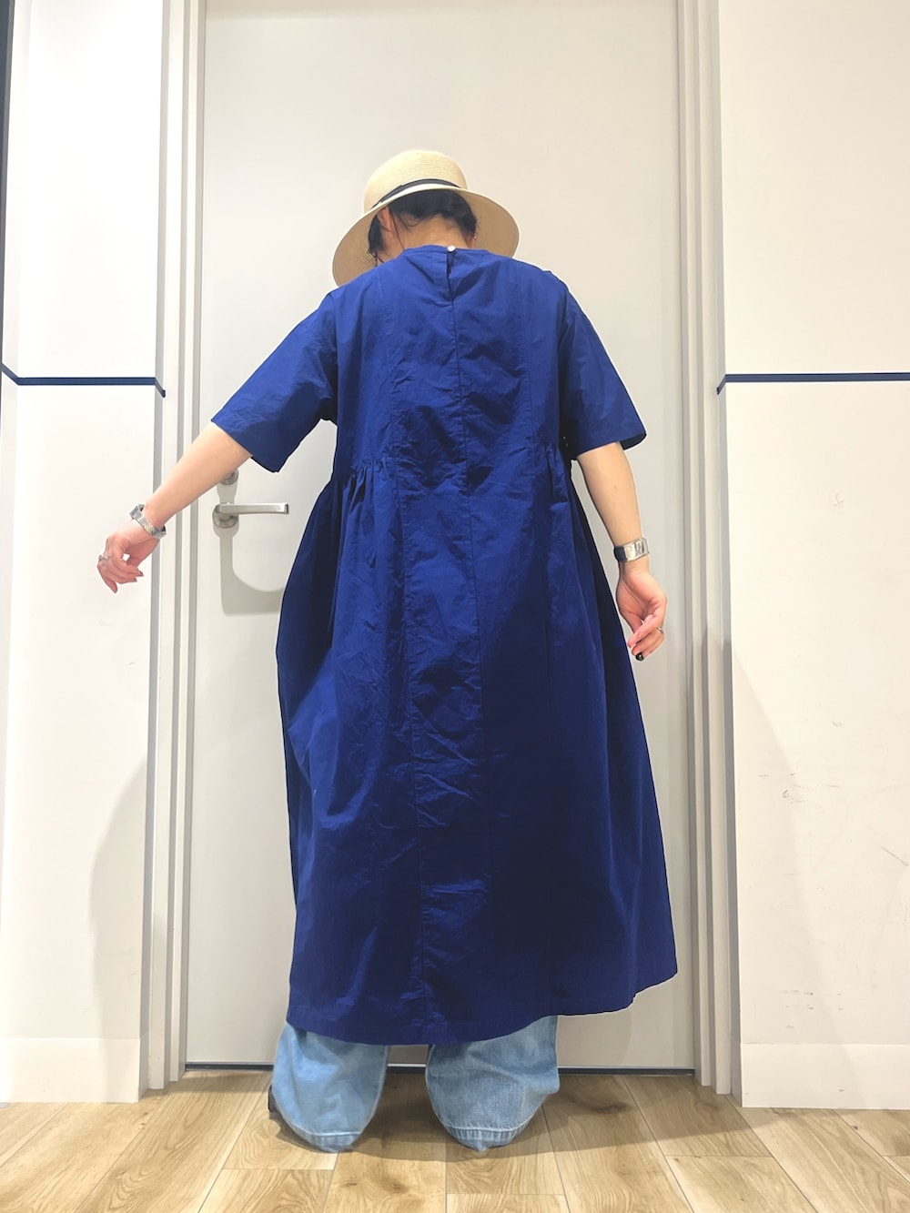 ブルー系のワンピース、ブルー系のトートバッグ、ブルー系のデニムパンツを着用したレディースの夏コーディネートの3枚目の写真